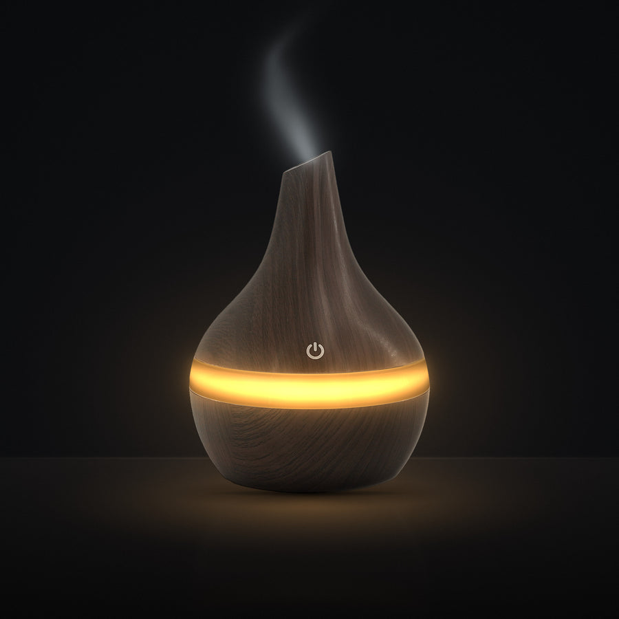 LUMUNO Aroma Diffuser in Walnut with cool mist rising and a warm amber glow